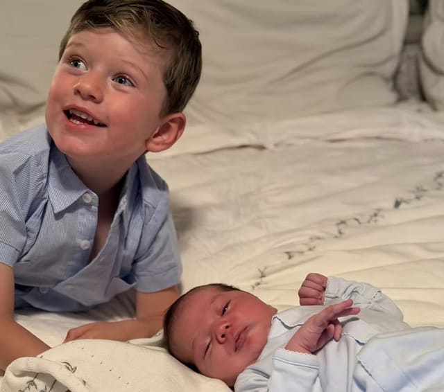 Their older son smiling next to his newborn baby brother
